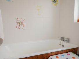 A bathroom with a bathtub and wall artwork at 20 Lym Close