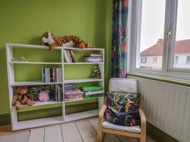 A room with a bookshelf and chair at 20 Lym Close in Lyme Regis