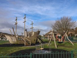 A playground with a pirate ship play structure and swings at 20 Lym Close in Lyme Regis