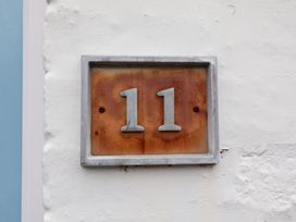 A house number 11 attached to a white wall at Deben Road in Woodbridge