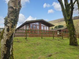 A log cabin with a deck and trees at Wansfell 2 Limefitt Park near Troutbeck