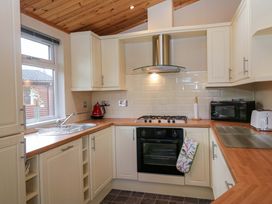 A kitchen with cabinets, cooking range, sink, and microwave at Wansfell 2 in Limefitt Park near Troutbeck