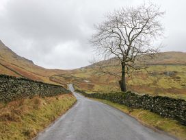 A road with a tree and stone walls along the sides in a mountain area