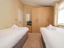 A bedroom with two beds and a wardrobe at Wansfell 2 in Limefitt Park near Troutbeck