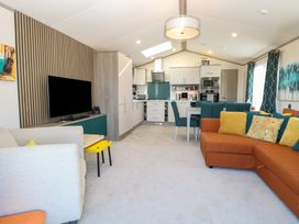 A living room with a sofa and dining area at Sand & Serenity in Bacton