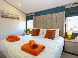 A bedroom with a bed and orange towels at Sand & Serenity in Bacton