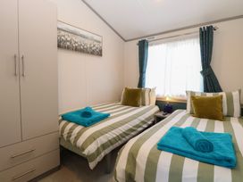 A bedroom with two beds and a wardrobe at Sand & Serenity in Bacton