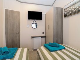 A bedroom with two beds and a television at Sand & Serenity in Bacton