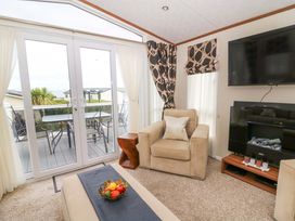 A living room with double doors leading to a deck at Ty Seren in New Quay