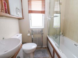 A bathroom featuring a sink, toilet, bathtub, and shower at Ty Seren in New Quay