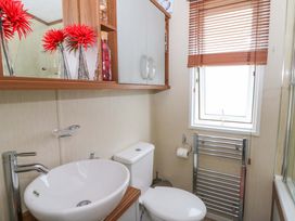 A bathroom with a sink, toilet, and mirror at Ty Seren in New Quay