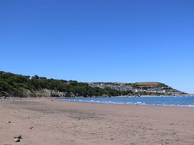 A beach with water and cliffs in the background at Ty Seren in New Quay