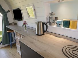 A small kitchen area with a kettle flowers on the counter a coffee press mugs and containers at Florence Pod in Pembroke