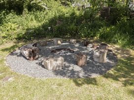 An outdoor fire pit area with tree stump seats arranged in a circle and a gravel ground at Florence Pod in Pembroke