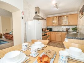 A kitchen with wooden cabinets a dining table set with cups plates and bread at Old Malthouse Apartment in Weymouth