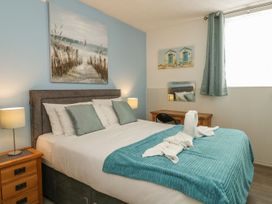 A bedroom with a double bed side tables lamps a desk chair and paintings at Old Malthouse Apartment in Weymouth