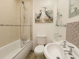 A bathroom with a bathtub shower combination a toilet a sink and wall art of birds at Old Malthouse Apartment in Weymouth