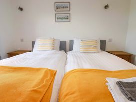 A bedroom with two beds and bedside tables at Sea Thrift in White Cross near Indian Queens
