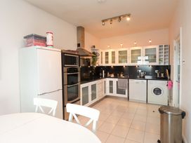 A kitchen with appliances and a dining table at Sea Views No 8 Plas Darien in Trearddur Bay