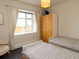 A bedroom with two beds and a wardrobe at Sea Views No 8 Plas Darien in Trearddur Bay