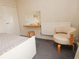 A bedroom with a bed, a mirror, a chair, and a stool at Sea Views No 8 Plas Darien Trearddur Bay
