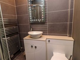 A bathroom with a shower, toilet, sink, mirror, and towel radiator at Sea Views No 8 Plas Darien in Trearddur Bay