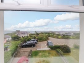 A view from a window showing cars in a parking lot and surrounding grass at Sea Views No 8 Plas Darien in Trearddur Bay