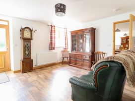 A living room with a clock and a cabinet at Gwernffridd