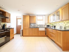 A kitchen with wooden cabinets and appliances at Gwernffridd