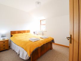 A bedroom with a yellow bedspread and bedside table at Gwernffridd