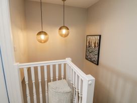 A staircase with lights hanging above and artwork on the wall at 1 Island View Thurlestone