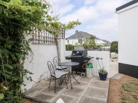 An outdoor dining area with a table and chairs beside a barbecue grill at 1 Island View Thurlestone