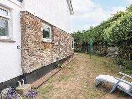 A garden with a stone wall, windows, and a deck chair at 1 Island View, Thurlestone