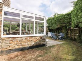 A conservatory with a dining table and garden at 1 Island View Thurlestone