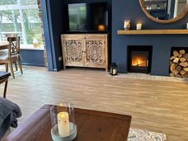 A living room with a television, wooden cabinet, and a fireplace at Thurlestone, 1 Island View in Thurlestone
