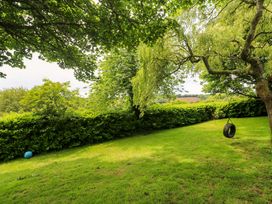 A garden with a tire swing and trees at The Cow Shed in 