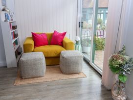 A living room with a yellow sofa and pink cushions at Old Felixstowe, Bath Road, Felixstowe, Suffolk