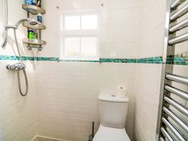 A bathroom with a shower, toilet, and window at 2 The Square Hope Cove