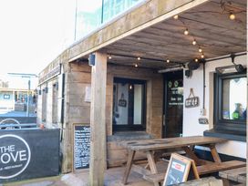 An outdoor seating area with tables and a menu board at The Cove in Hope Cove