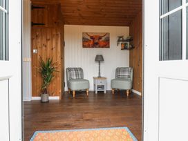 A seating area with two chairs a small table and a lamp a plant and a painting on the wall at The Heron in Lode near Bottisham