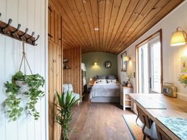 A bedroom with wooden ceiling and floor a bed desk chair and plants at The Heron in Lode near Bottisham