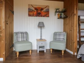 A sitting area with two chairs a side table and lamp under a painting of a highland cow at The Heron in Lode near Bottisham