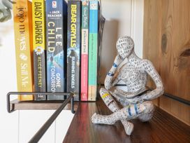 A wooden shelf with several books and a small figurine of a person reading at The Heron in Lode near Bottisham