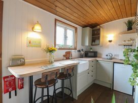 A kitchen with wooden countertops bar stools a sink microwave and fridge at The Heron in Lode near Bottisham