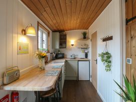 A small kitchen with wooden countertops stools a microwave and plants at The Heron in Lode near Bottisham