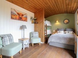 A bedroom with a double bed pillows two single chairs and bunk beds at The Heron in Lode near Bottisham