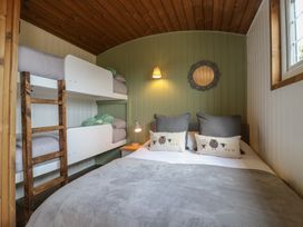 A bedroom with a double bed and bunk beds a wall lamp and a window at The Heron in Lode near Bottisham