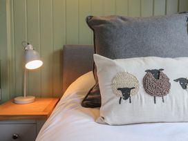 A bed with grey and white pillows and a bedside table with a lamp at The Heron in Lode near Bottisham