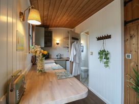 A kitchen area with wooden countertops flowers in a vase and two white bathrobes hanging on the door at The Heron in Lode near Bottisham