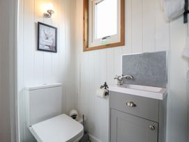 A small bathroom with a toilet sink cabinet and window at The Heron in Lode near Bottisham